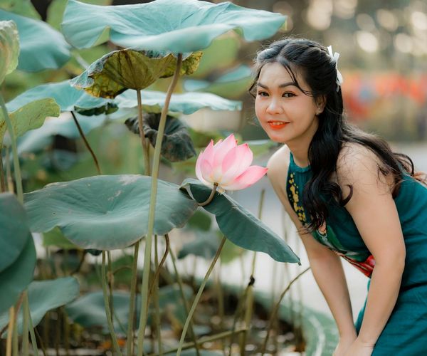 Woman smiling peacefully while sitting outdoors.